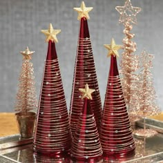 three red christmas trees sitting on top of a metal tray next to small gold stars