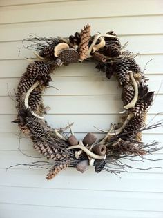 a wreath with pine cones and antlers hanging on the side of a house,