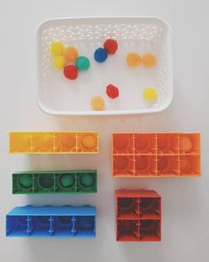 three plastic trays filled with different colored balls on top of a white table next to each other