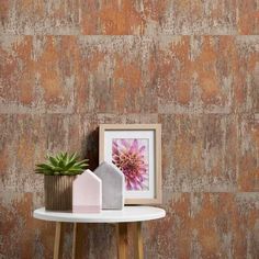 a small table with a potted plant on it next to a wallpapered background