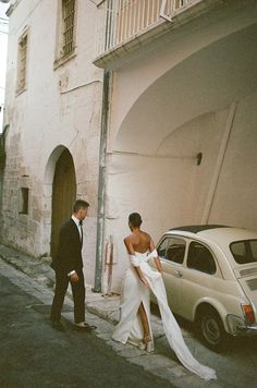 a man and woman standing next to a white car