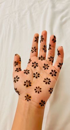 a person's hand with black flowers painted on it and the palm of their left hand