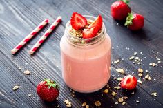 a jar filled with yogurt and strawberries on top of a wooden table