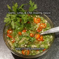 a glass bowl filled with soup and garnished with cilantro, carrots, parsley