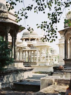 an old building with many pillars and arches in the foreground, surrounded by trees