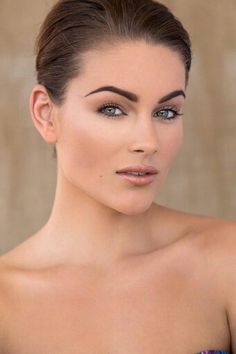 a woman in a strapless dress posing for the camera with blue eyeshadow