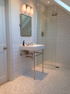 a bathroom with a sink, mirror and shower stall in white tile on the wall