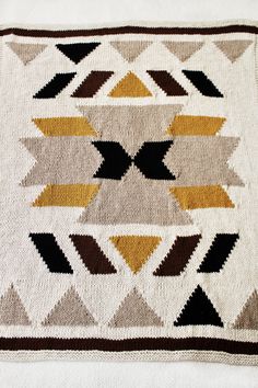 a white blanket with brown and yellow designs on it