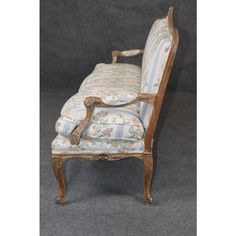 an antique chair with floral upholstered fabric and wood frame, on grey background