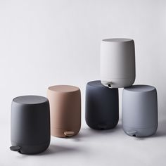 four different colored stools sitting next to each other on a white surface in front of a wall