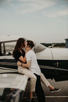 a man and woman kissing in front of an airplane