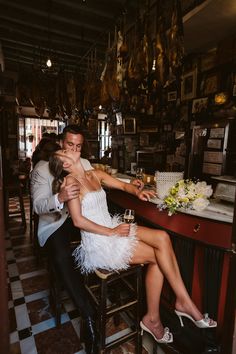 a man and woman sitting at a bar with their arms around each other as they kiss