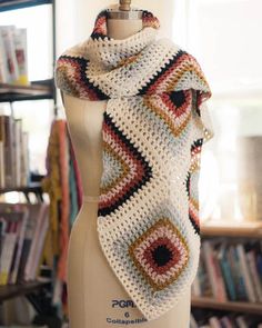 a white mannequin with a crocheted scarf on it