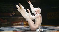 a woman dressed in white poses on the floor with her legs spread out and feet up