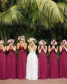 a group of women standing next to each other in front of plants and palm trees