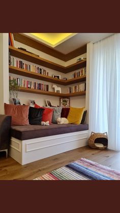 a living room filled with lots of furniture and bookshelves next to a window