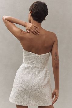 the back of a woman's white dress, with her hand on her shoulder