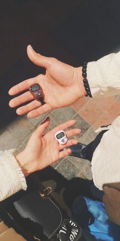 two people are holding their cell phones in one hand and the other is wearing a watch