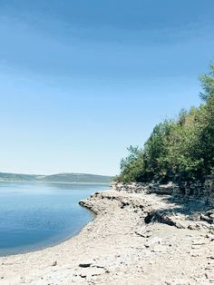 an empty beach with trees and water in the background