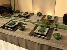 the table is set with green dishes and place settings