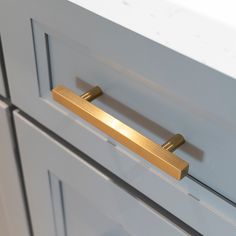 a close up of a drawer handle on a white cabinet with gold handles and knobs