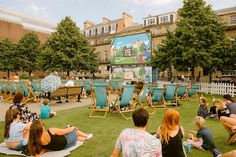 people sitting on lawn chairs in front of a large screen with an image of peter panton