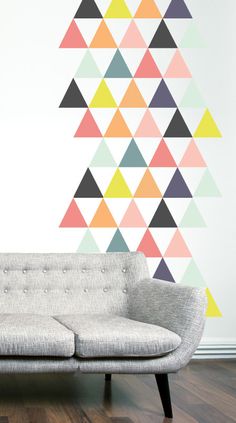 a couch sitting in front of a wall with colorful triangles on it's side