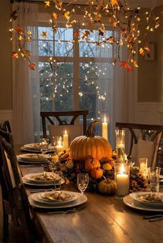 a dining room table with candles, plates and pumpkins