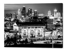 a black and white photo of the city skyline at night with lights in the buildings