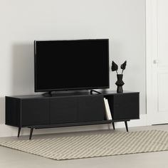 a flat screen tv sitting on top of a black entertainment center next to a vase with flowers