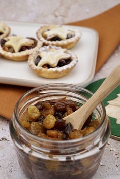 some food is in a glass jar and on a plate with a wooden spoon next to it