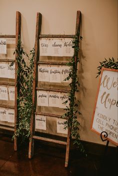 an old ladder is decorated with greenery and seating cards