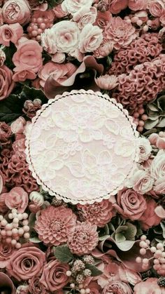 a white doily surrounded by pink flowers and greenery