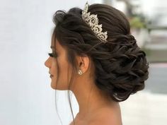 a woman wearing a tiara looking off into the distance with her hair in a low bun