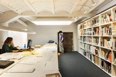 two people sitting at desks in a library with bookshelves full of books