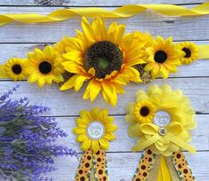 three sunflowers and two ribbons on a white wooden surface with flowers in the background