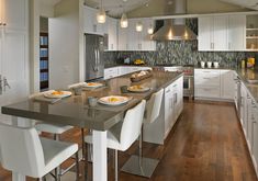 a large kitchen with white cabinets and wooden flooring, along with an island in the middle