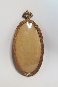 an antique watch is sitting on a white surface with a gold frame and chain around it