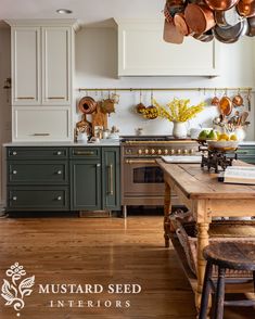 a kitchen with green cabinets and an island in the middle is surrounded by pots and pans