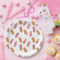 a paper plate with ice cream on it next to cupcakes and other decorations