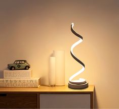 a lamp that is sitting on top of a table next to a book and a toy car