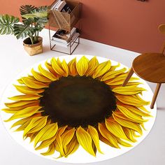 a large yellow sunflower is on the floor next to a chair and bookshelf