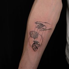 a person with a tattoo on their arm holding an object in the shape of a heart