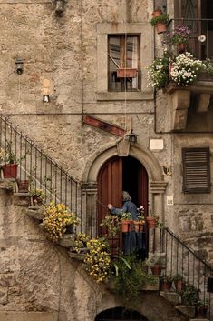 an old building with flowers growing on the balcony and steps leading up to the door