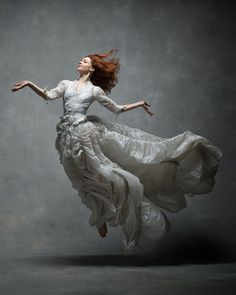 a woman in a white dress is flying through the air with her arms spread out