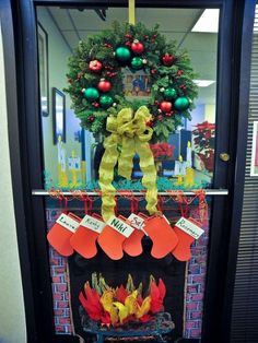 a christmas wreath on top of a fire place with stockings hanging from the front door