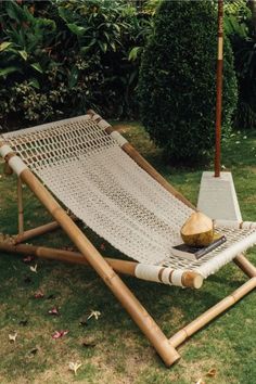 a hammock is sitting in the grass with an umbrella over it and some wood sticks