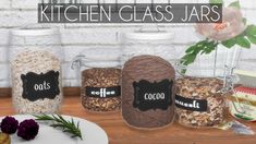 kitchen glass jars with labels on them sitting on a table next to flowers and other items