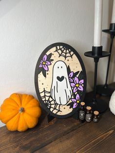 a wooden table topped with candles and a halloween decoration next to a white candle holder