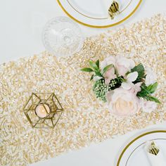 the table is decorated with gold sequins and white flowers, candles and plates